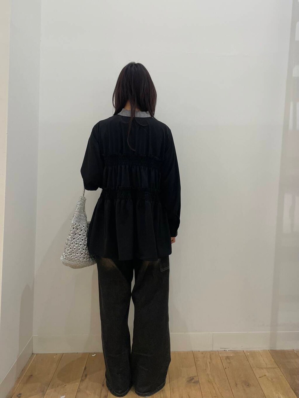 ブラック系のデニムパンツ、シルバー系のハンドバッグ、グレー系のニット/セーターを着用したレディースの春コーディネートの3枚目の写真