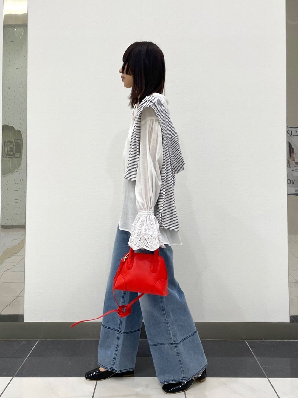 ホワイト系のシャツ/ブラウス、ブルー系のデニムパンツ、レッド系のショルダーバッグを着用したレディースの春コーディネートの2枚目の写真