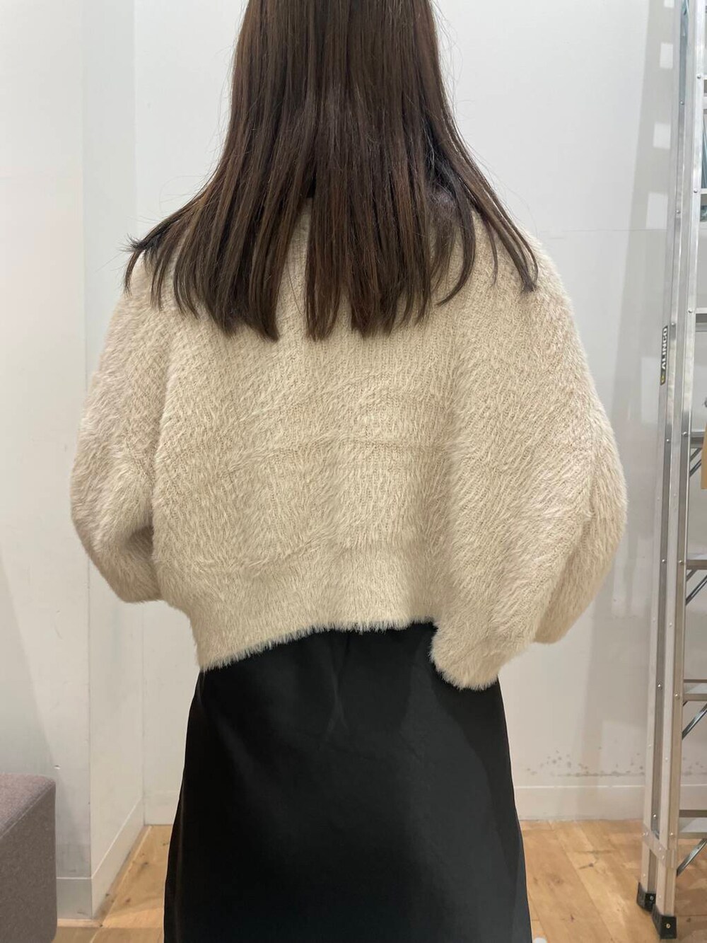 ベージュ系のニット/セーター、ブラウン系のハンドバッグ、ブラウン系のブーツを着用したレディースの秋コーディネートの5枚目の写真