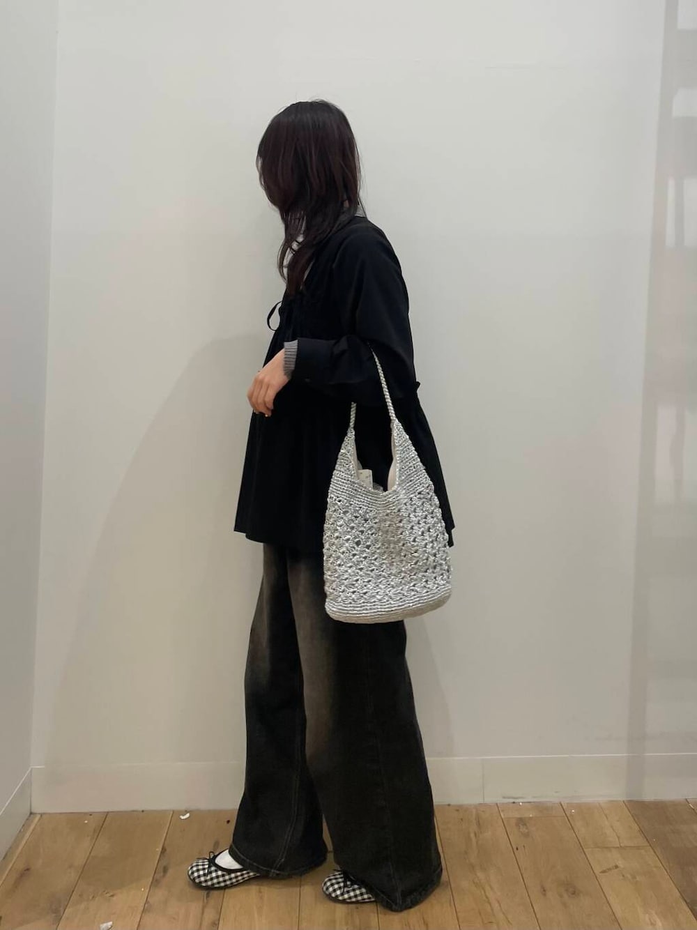 ブラック系のデニムパンツ、シルバー系のハンドバッグ、グレー系のニット/セーターを着用したレディースの春コーディネートの2枚目の写真