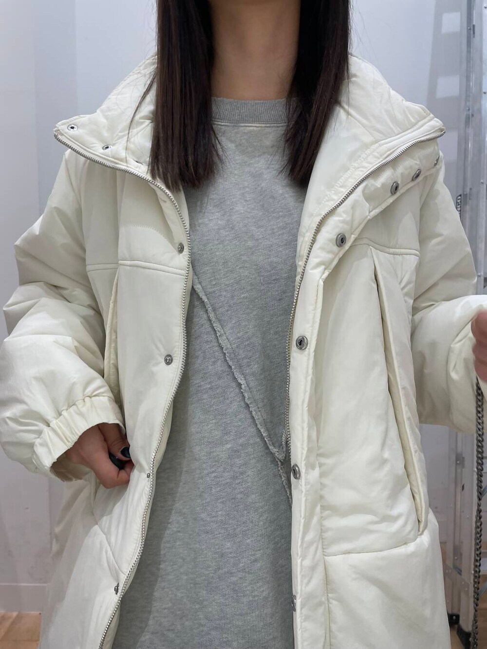 ブルー系のスカート、グレー系のTシャツ/カットソー、ホワイト系のダウンジャケット/コートを着用したレディースの秋コーディネートの4枚目の写真