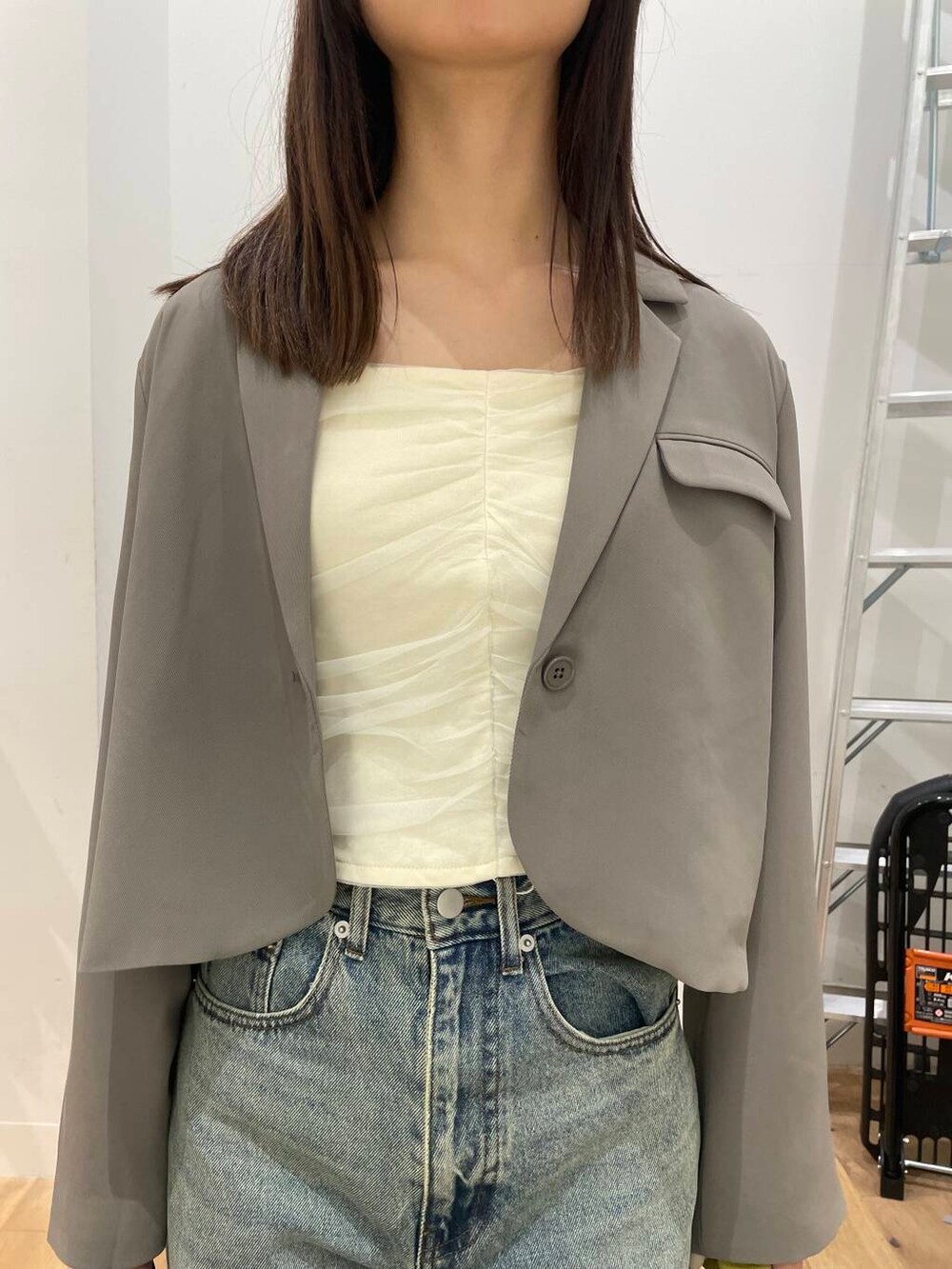 イエロー系のハンドバッグ、ブラック系のその他シューズ、ブルー系のデニムパンツを着用したレディースの秋コーディネートの4枚目の写真