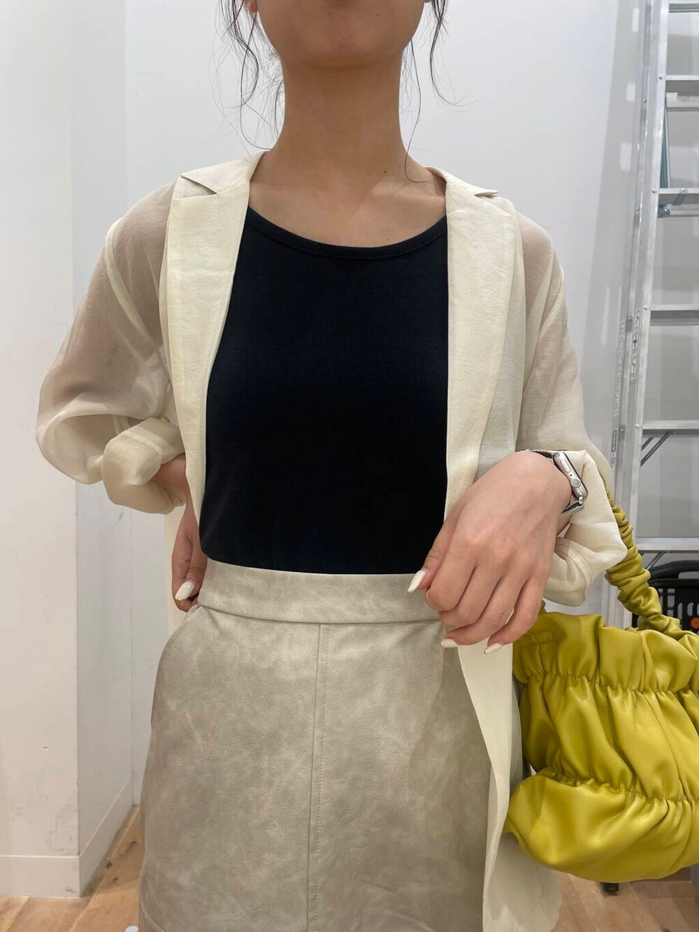 イエロー系のハンドバッグ、ブラック系のTシャツ/カットソー、ブラック系のサンダルを着用したレディースの秋コーディネートの4枚目の写真