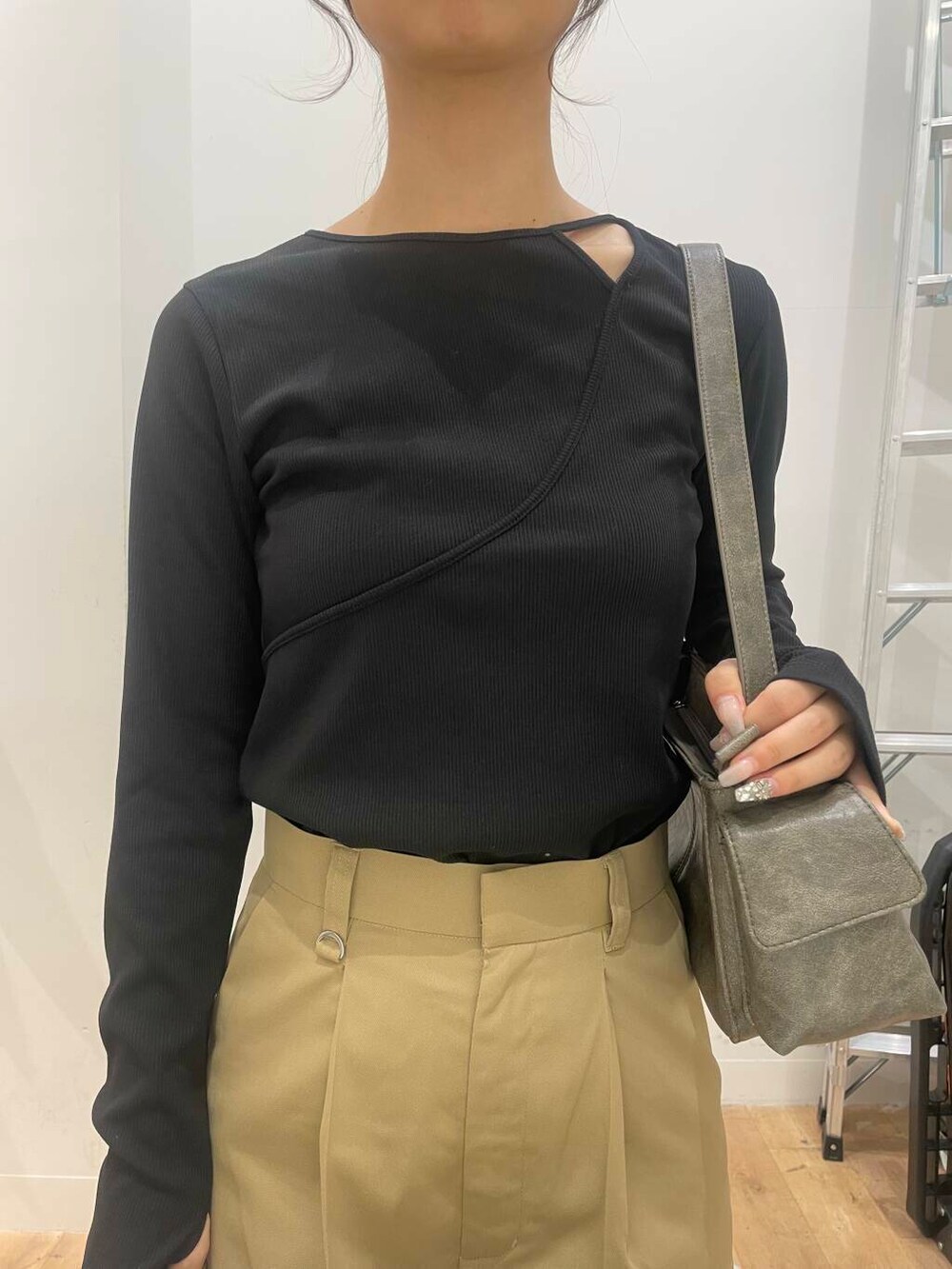 グレー系のハンドバッグ、ゴールド系のブーツ、ブラック系のTシャツ/カットソーを着用したレディースの秋コーディネートの4枚目の写真