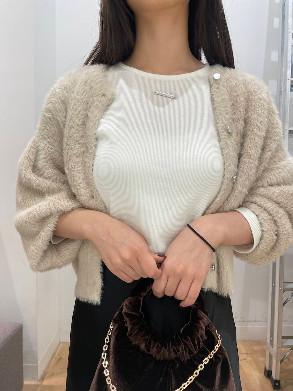 ベージュ系のニット/セーター、ブラウン系のハンドバッグ、ブラウン系のブーツを着用したレディースの秋コーディネートの4枚目の写真