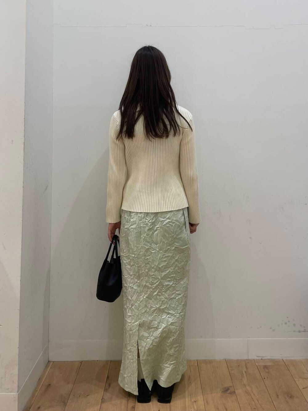 ブラック系のショルダーバッグ、ホワイト系のニット/セーター、グリーン系のスカートを着用したレディースの春コーディネートの3枚目の写真