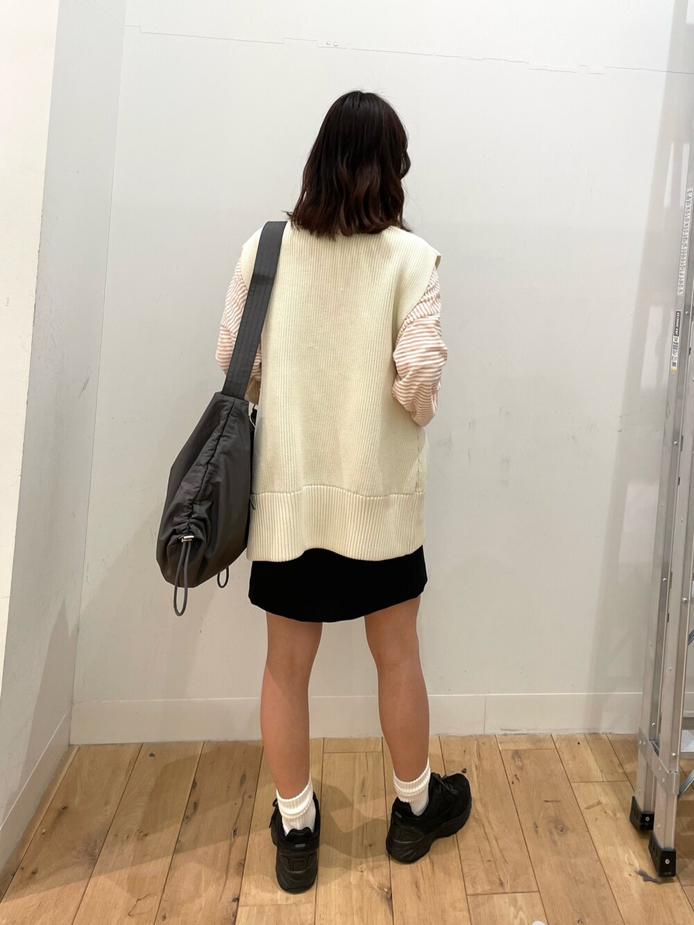 ブラック系のスカート、ホワイト系のベスト、グレー系のショルダーバッグを着用したレディースの春コーディネートの3枚目の写真