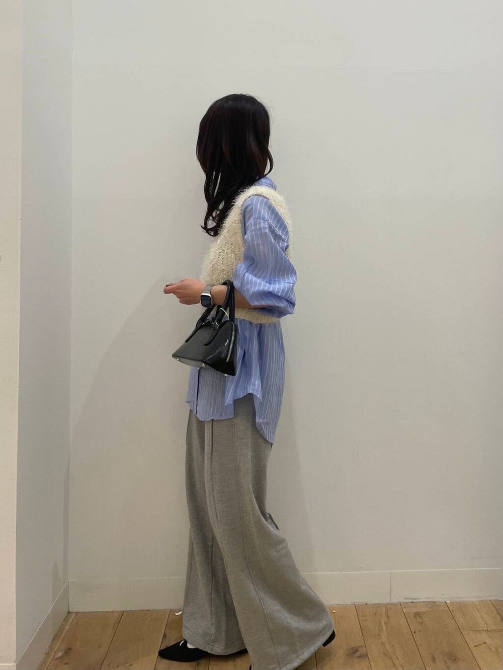 ブラック系のボストンバッグ、ホワイト系のベスト、ブルー系のシャツ/ブラウスを着用したレディースの春コーディネートの2枚目の写真