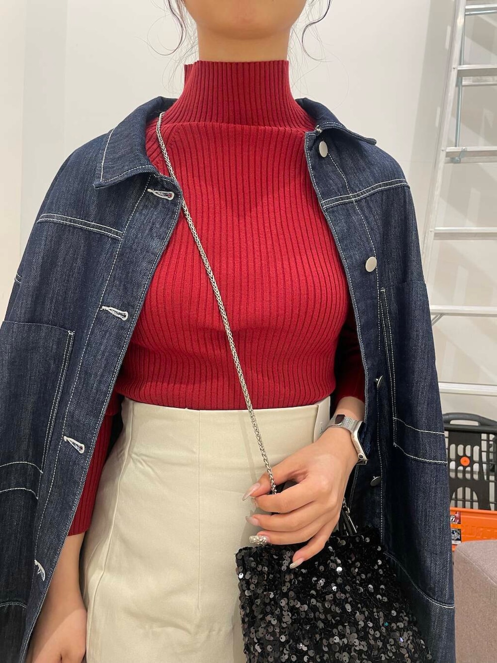 ブラック系のショルダーバッグ、レッド系のニット/セーター、ベージュ系のスカートを着用したレディースの秋コーディネートの4枚目の写真