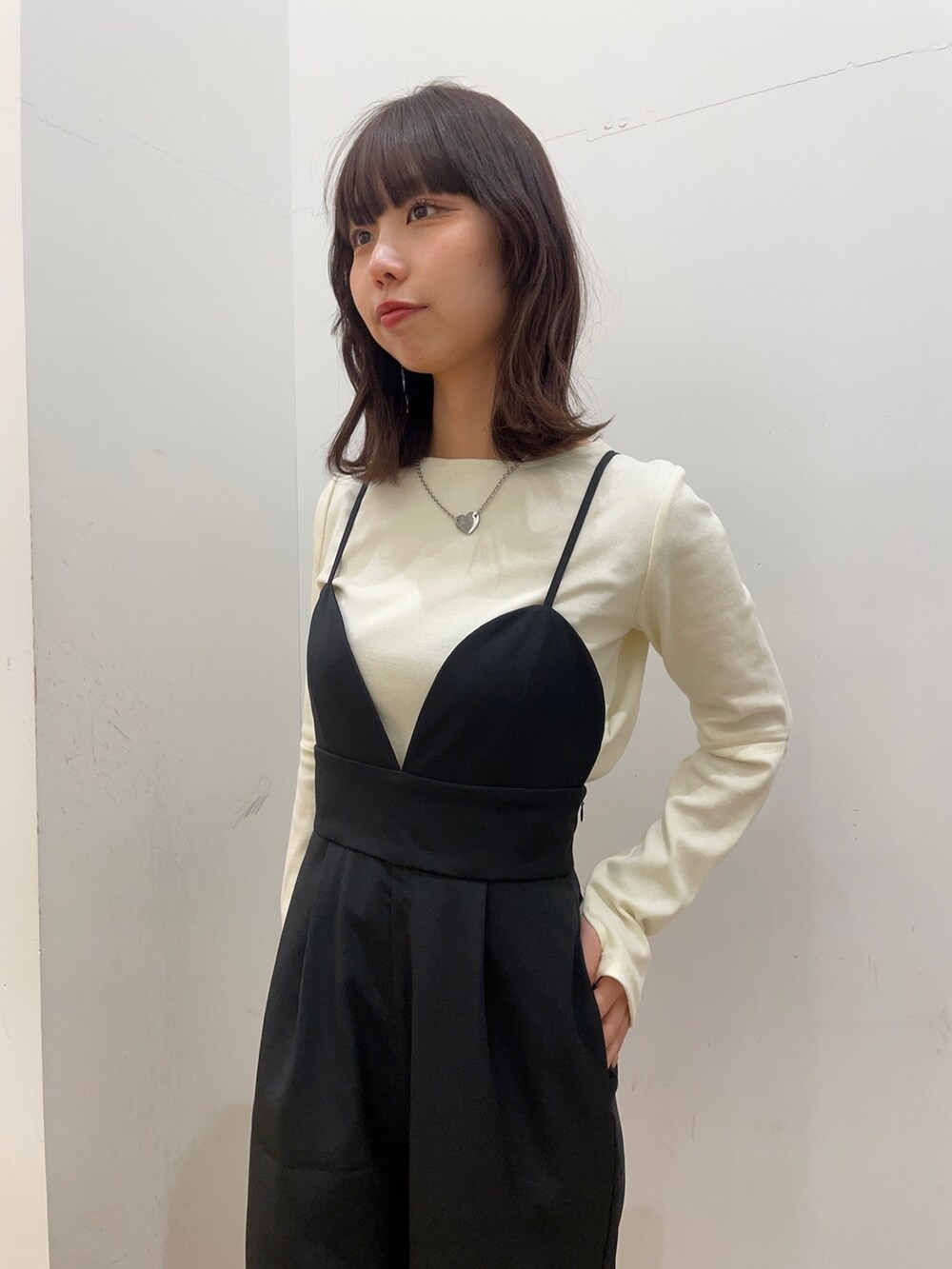 ブラック系のサロペット/オーバーオール、ホワイト系のTシャツ/カットソー、ゴールド系のサンダルを着用したレディースの春コーディネートの3枚目の写真
