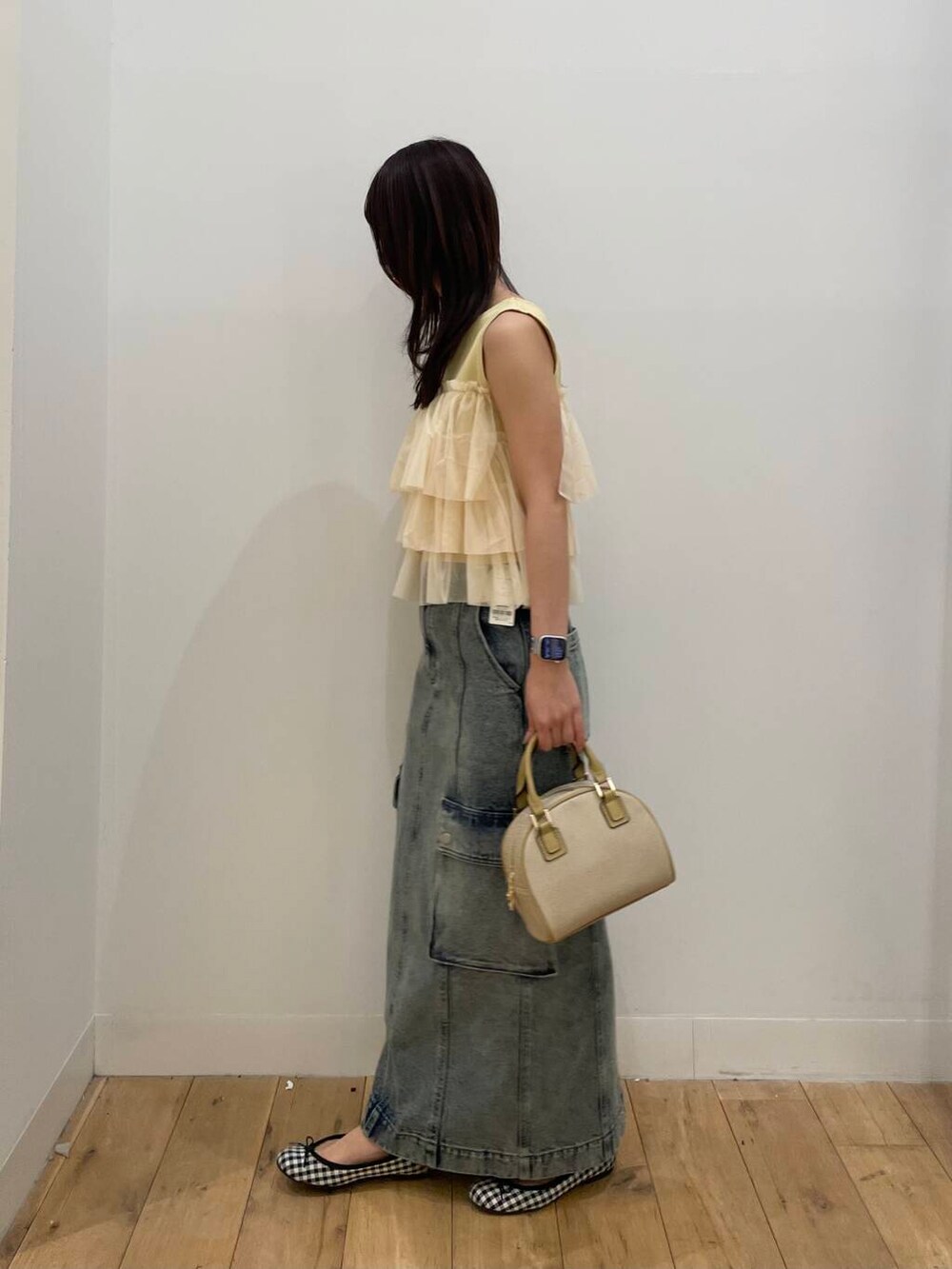 ベージュ系のボストンバッグ、ブルー系のスカート、イエロー系のニット/セーターを着用したレディースの春コーディネートの2枚目の写真