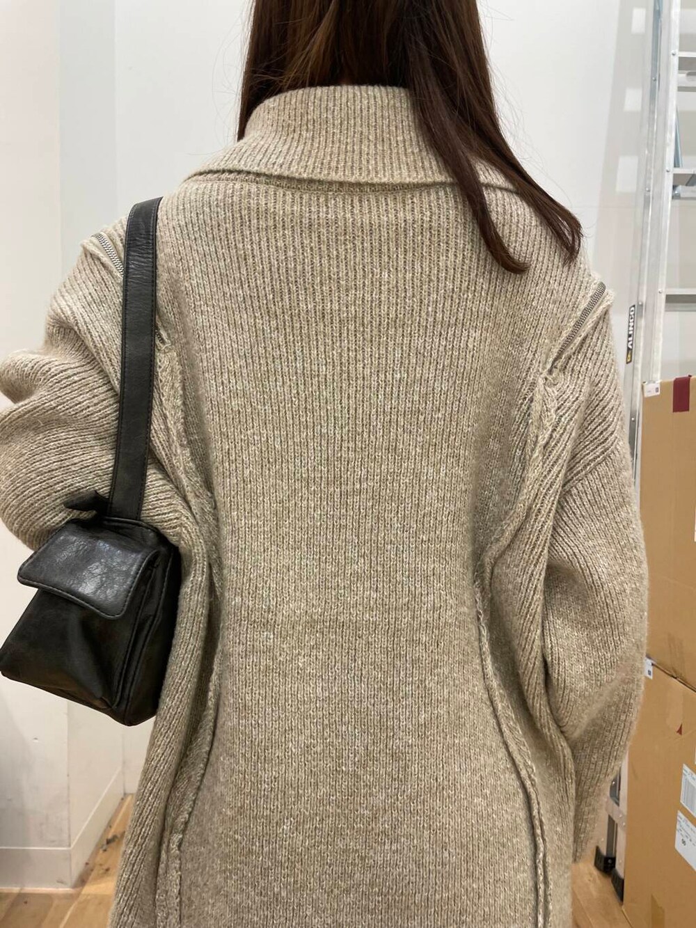 ベージュ系のニット/セーター、グレー系のハンドバッグ、ブルー系のスカートを着用したレディースの秋コーディネートの5枚目の写真