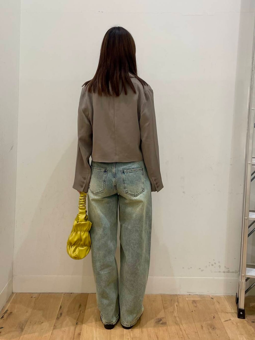 イエロー系のハンドバッグ、ブラック系のその他シューズ、ブルー系のデニムパンツを着用したレディースの秋コーディネートの3枚目の写真