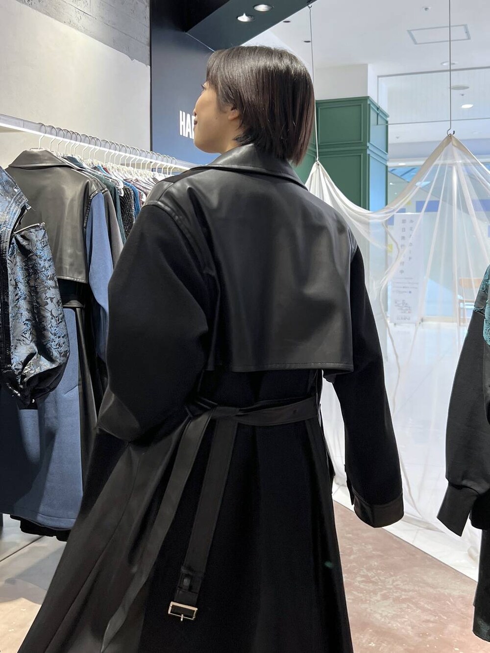 ブラック系のチェスターコート、レッド系のニット/セーター、ブラック系のブーツを着用したレディースの秋コーディネートの3枚目の写真