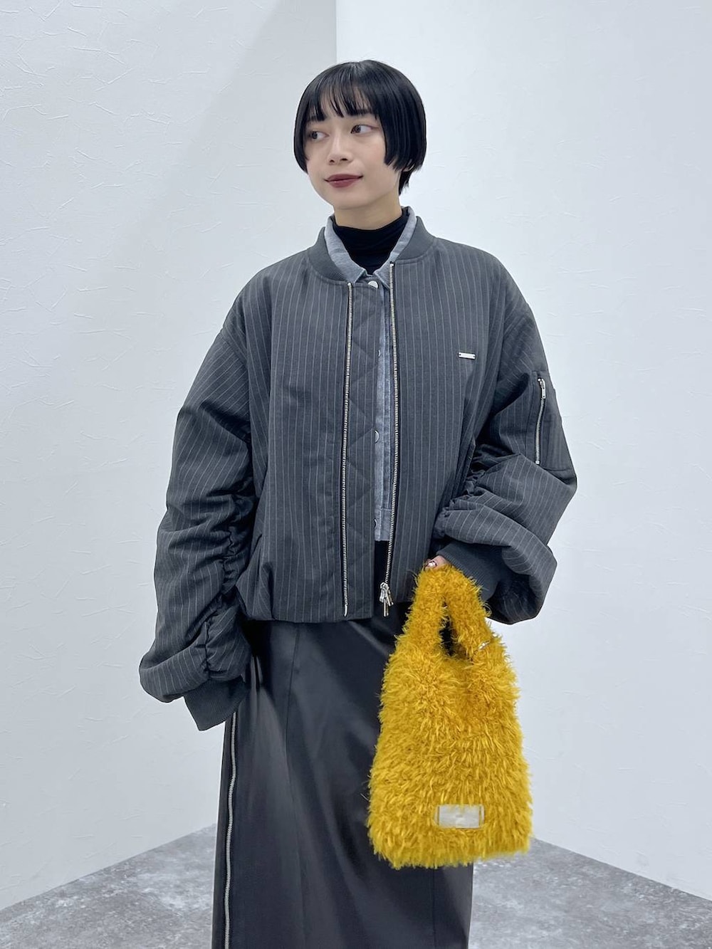 ブラック系のブーツ、イエロー系のショルダーバッグ、ブラック系のスカートを着用したレディースの秋コーディネートの2枚目の写真