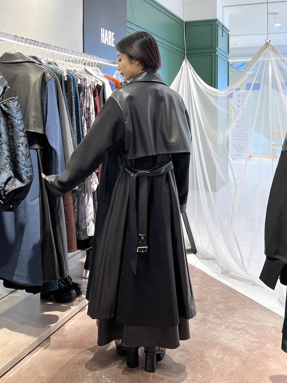 ブラック系のチェスターコート、レッド系のニット/セーター、ブラック系のブーツを着用したレディースの秋コーディネートの4枚目の写真