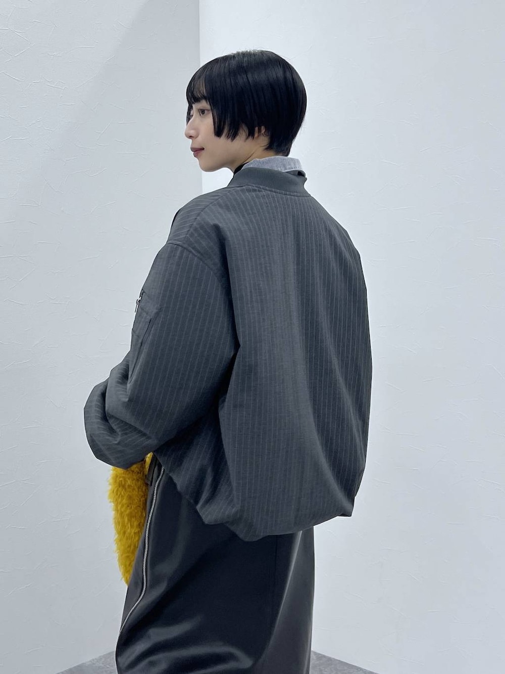 ブラック系のブーツ、イエロー系のショルダーバッグ、ブラック系のスカートを着用したレディースの秋コーディネートの3枚目の写真