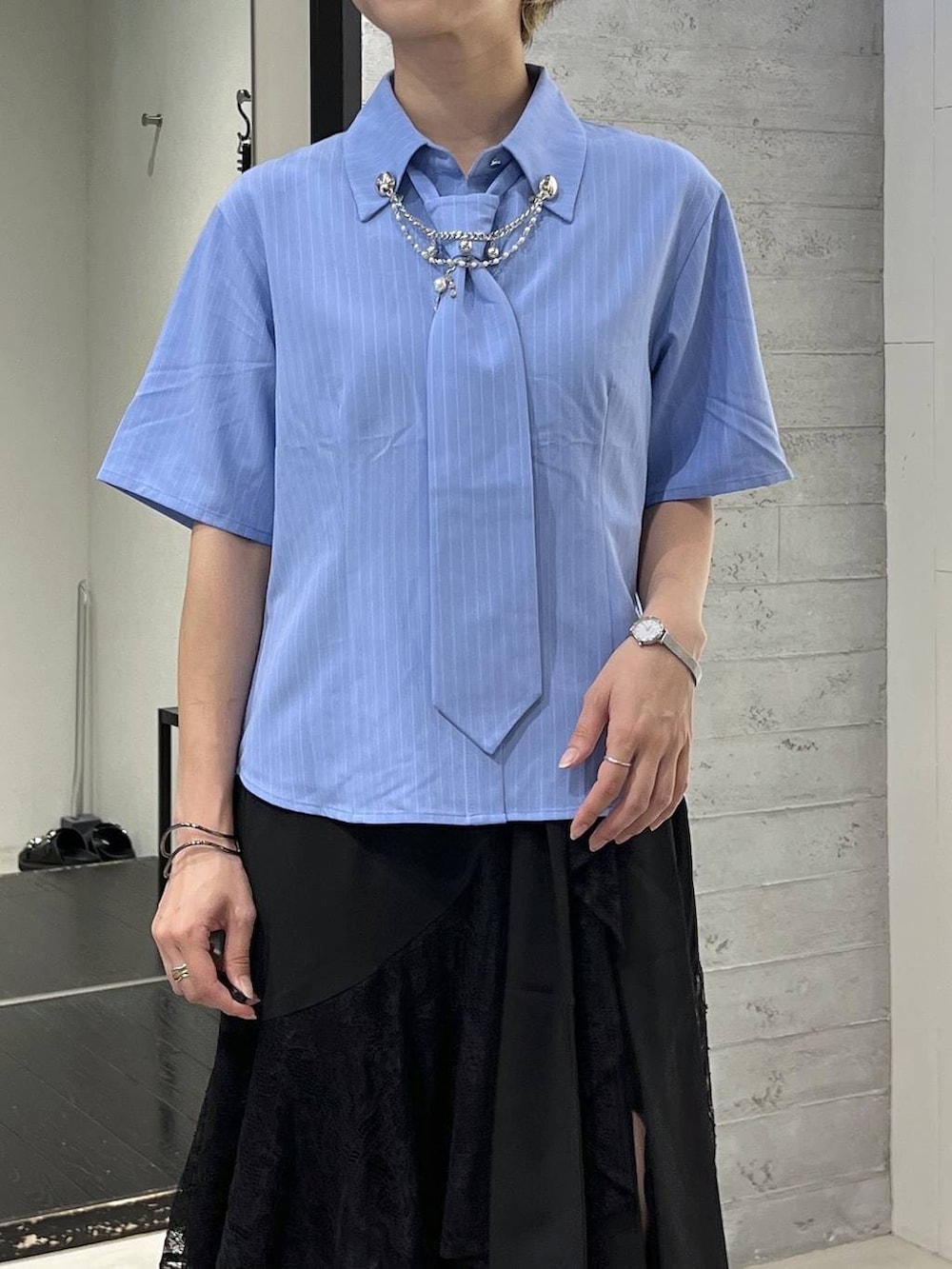 ブルー系のシャツ/ブラウス、ブラック系のサンダル、ブラック系のスカートを着用したレディースの夏コーディネートの2枚目の写真