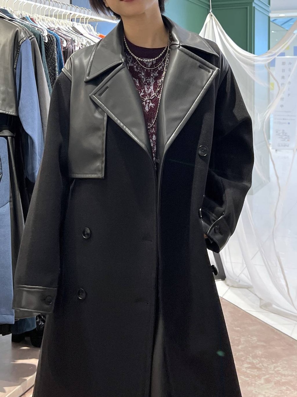 ブラック系のチェスターコート、レッド系のニット/セーター、ブラック系のブーツを着用したレディースの秋コーディネートの2枚目の写真