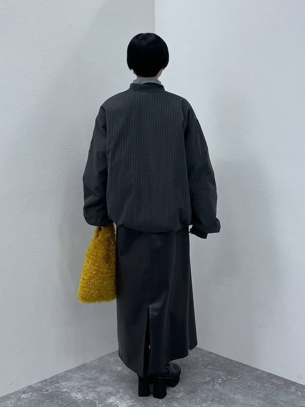 ブラック系のブーツ、イエロー系のショルダーバッグ、ブラック系のスカートを着用したレディースの秋コーディネートの4枚目の写真