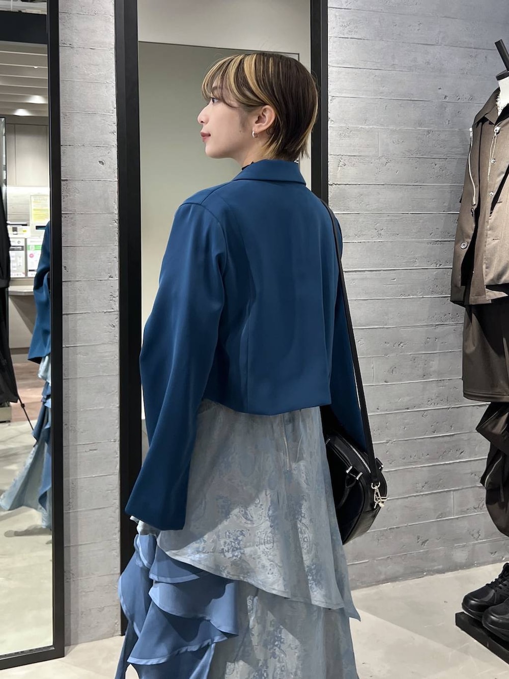 ブラック系のブーツ、グリーン系のテーラードジャケット、ブラック系のショルダーバッグを着用したレディースの春コーディネートの3枚目の写真