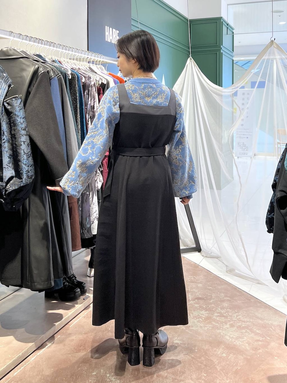 ブルー系のニット/セーター、ブラック系のブーツ、ブラック系のワンピースを着用したレディースの秋コーディネートの4枚目の写真