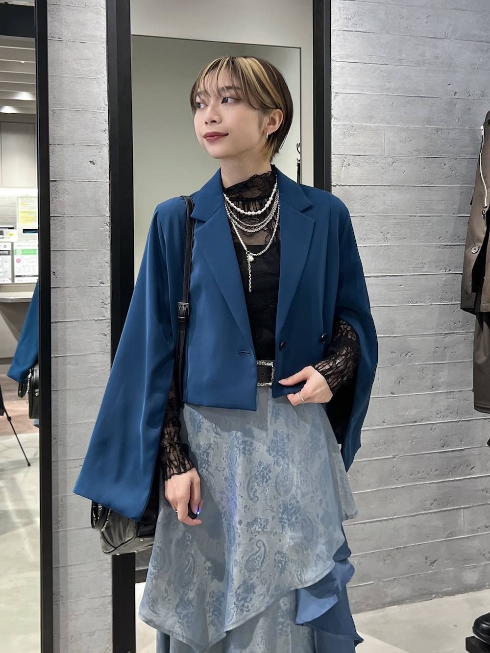 ブラック系のブーツ、グリーン系のテーラードジャケット、ブラック系のショルダーバッグを着用したレディースの春コーディネートの2枚目の写真