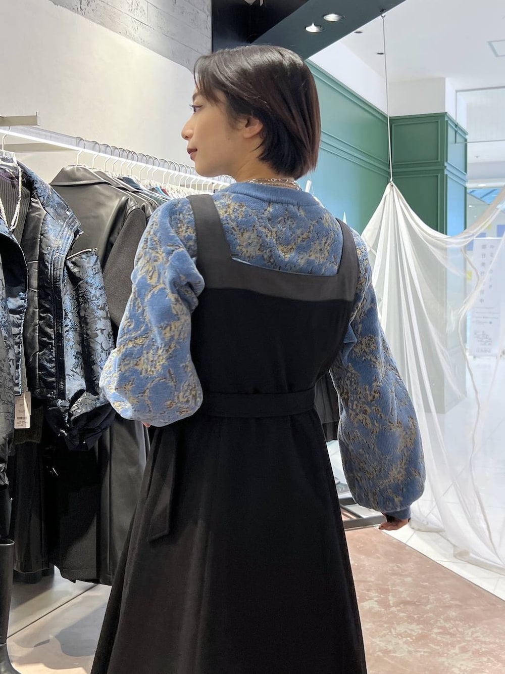 ブルー系のニット/セーター、ブラック系のブーツ、ブラック系のワンピースを着用したレディースの秋コーディネートの3枚目の写真