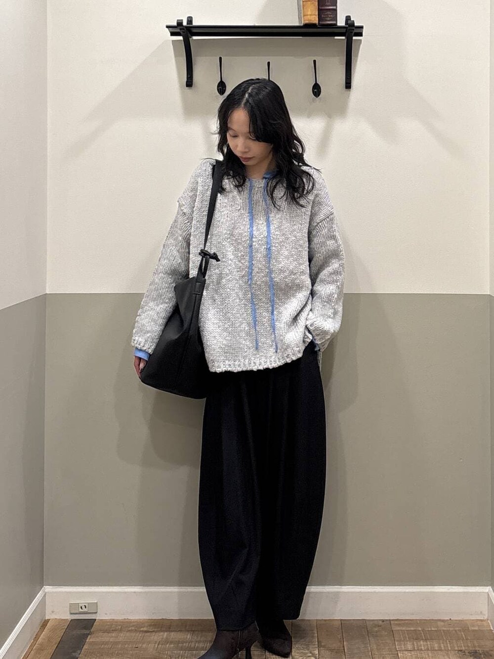 ブラック系のスラックス、グレー系のニット/セーター、ブラック系のトートバッグを着用したレディースの冬コーディネートの2枚目の写真