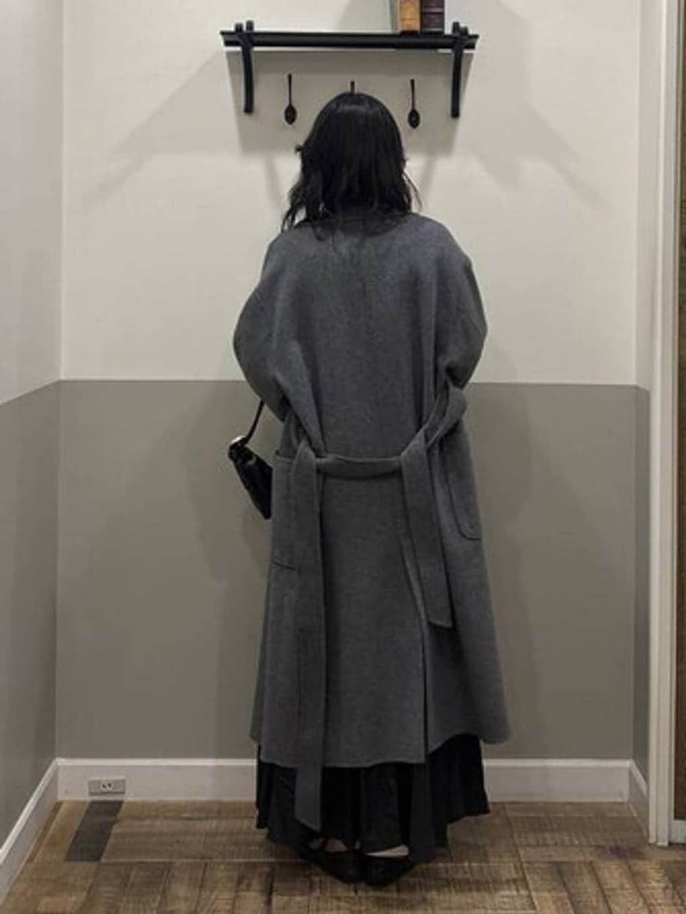 グレー系のステンカラーコート、ブラック系のショルダーバッグ、ホワイト系のニット/セーターを着用したレディースの冬コーディネートの3枚目の写真