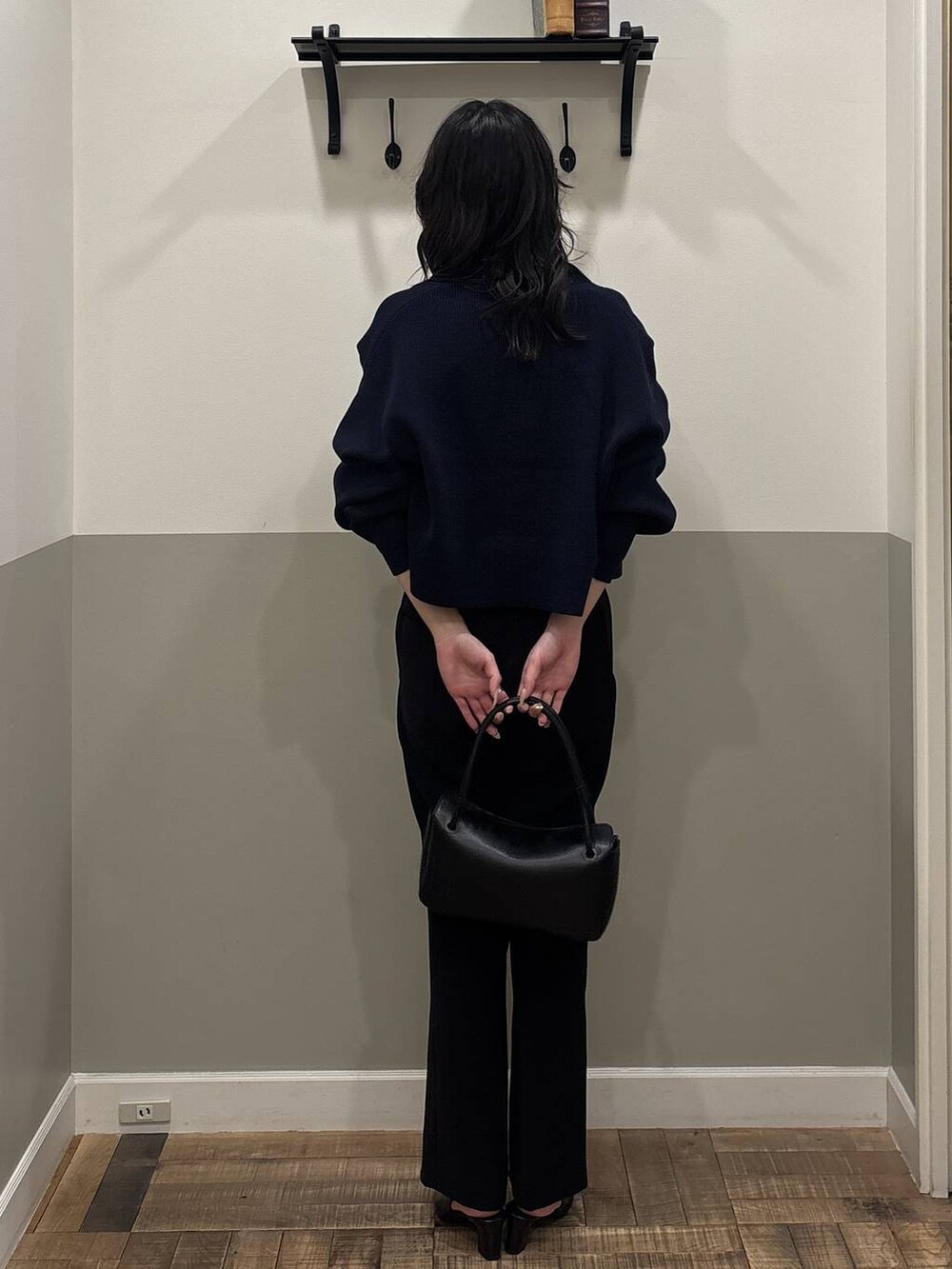 ブラック系のスラックス、ブラック系のパンプス、ブラック系のショルダーバッグを着用したレディースの冬コーディネートの3枚目の写真