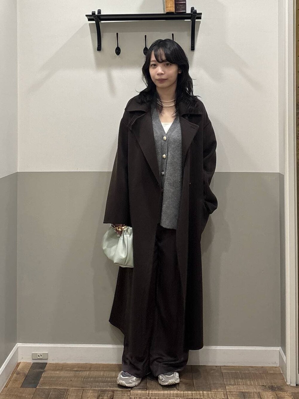 ブラウン系のステンカラーコート、グレー系のカーディガン/ボレロ、グリーン系のショルダーバッグを着用したレディースの秋コーディネートの4枚目の写真