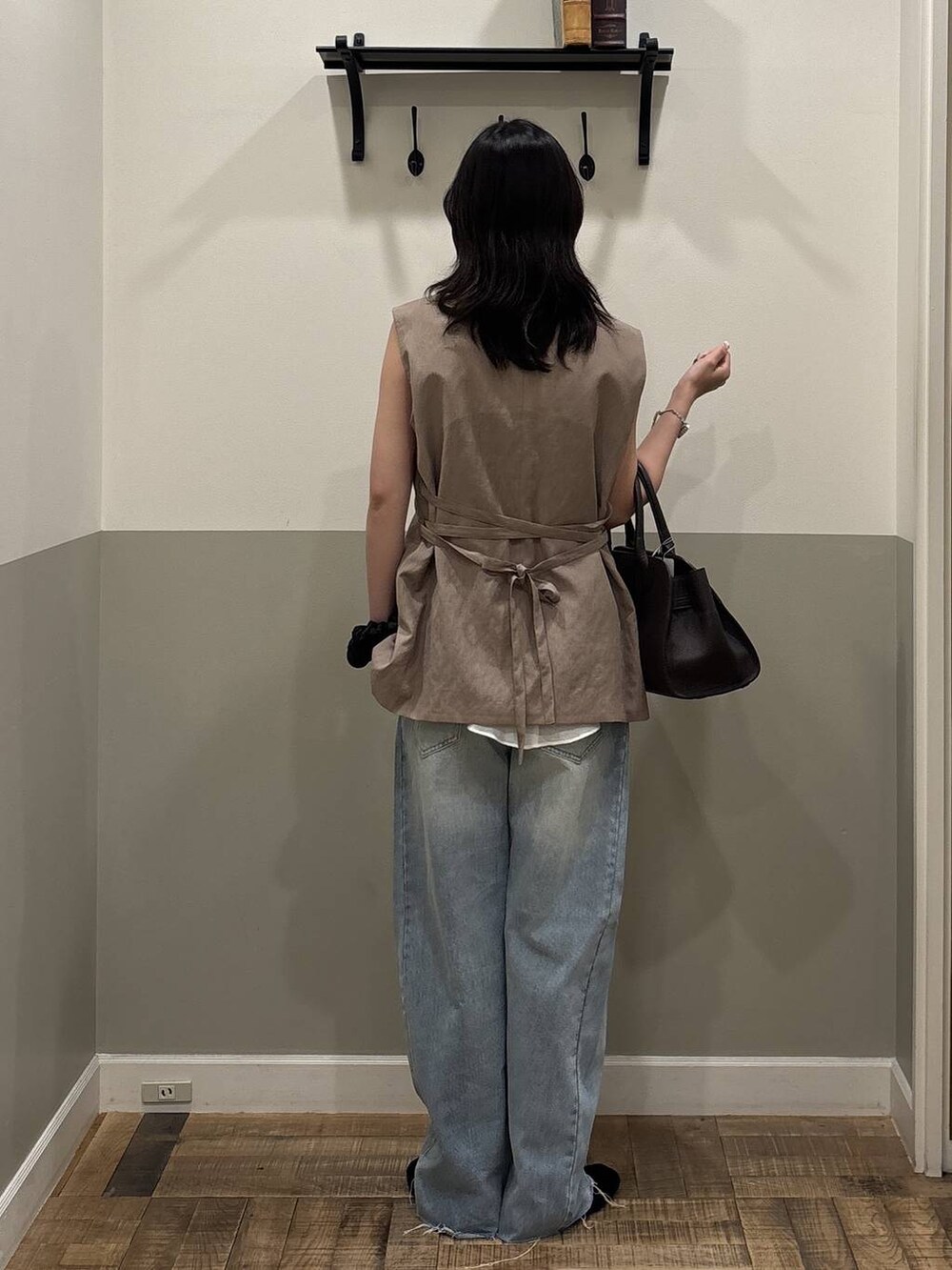 ブルー系のデニムパンツ、ブラック系のショルダーバッグ、グレー系のベストを着用したレディースの夏コーディネートの3枚目の写真