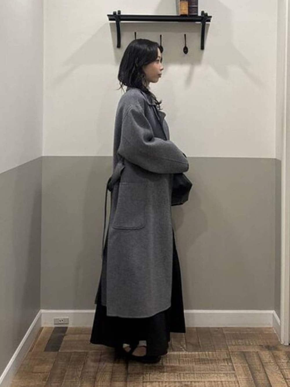 グレー系のステンカラーコート、ブラック系のショルダーバッグ、ホワイト系のニット/セーターを着用したレディースの冬コーディネートの2枚目の写真