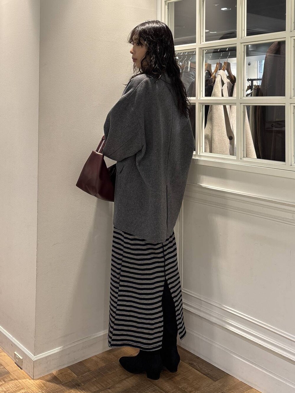 グレー系のテーラードジャケット、ブラック系のワンピース、ブラック系のブーツを着用したレディースの秋コーディネートの3枚目の写真