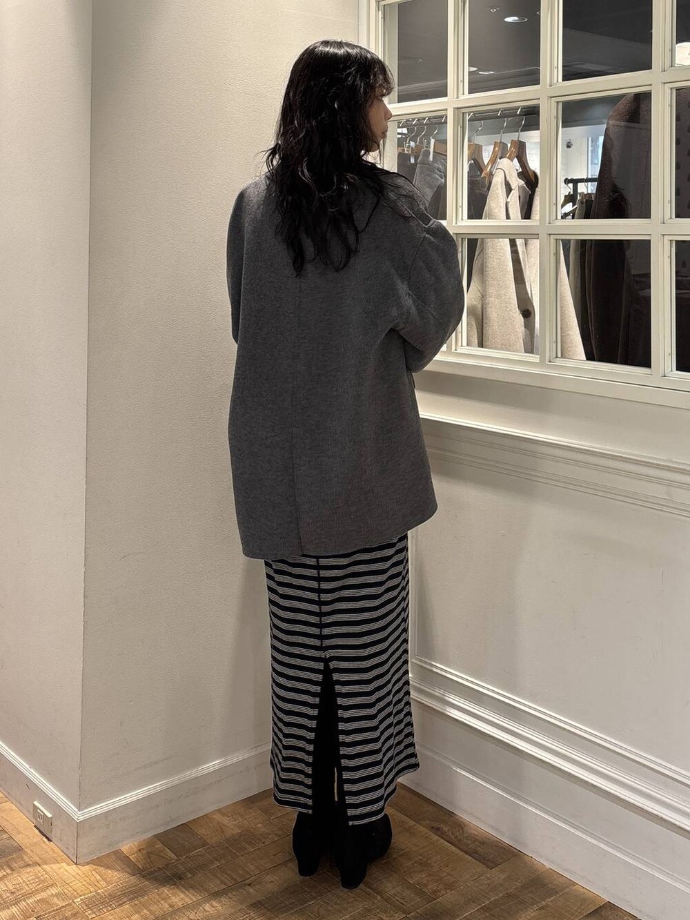 グレー系のテーラードジャケット、ブラック系のワンピース、ブラック系のブーツを着用したレディースの秋コーディネートの4枚目の写真