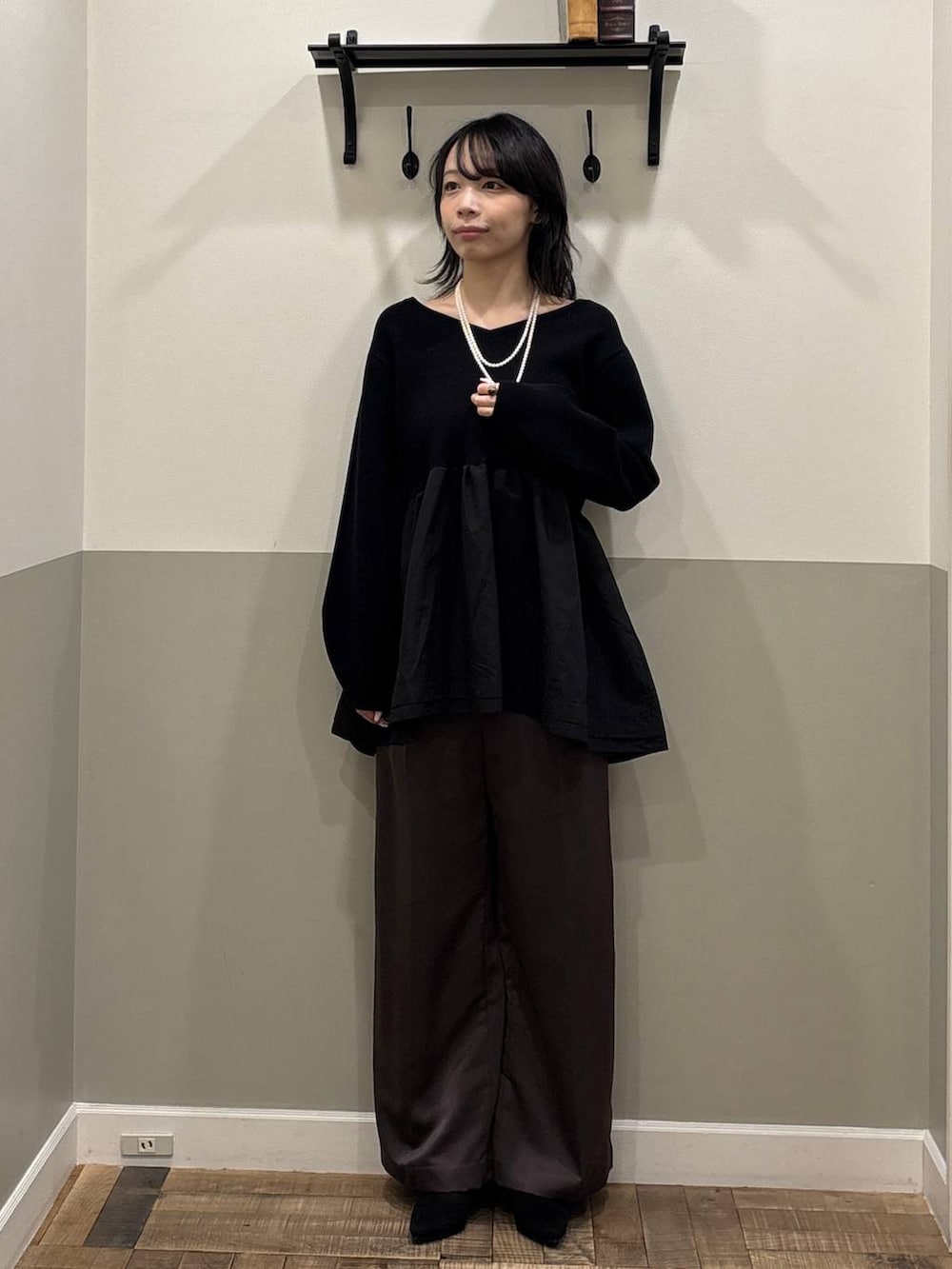 ブラウン系のスラックス、ブラック系のブーツ、ブラック系のニット/セーターを着用したレディースの冬コーディネートの2枚目の写真