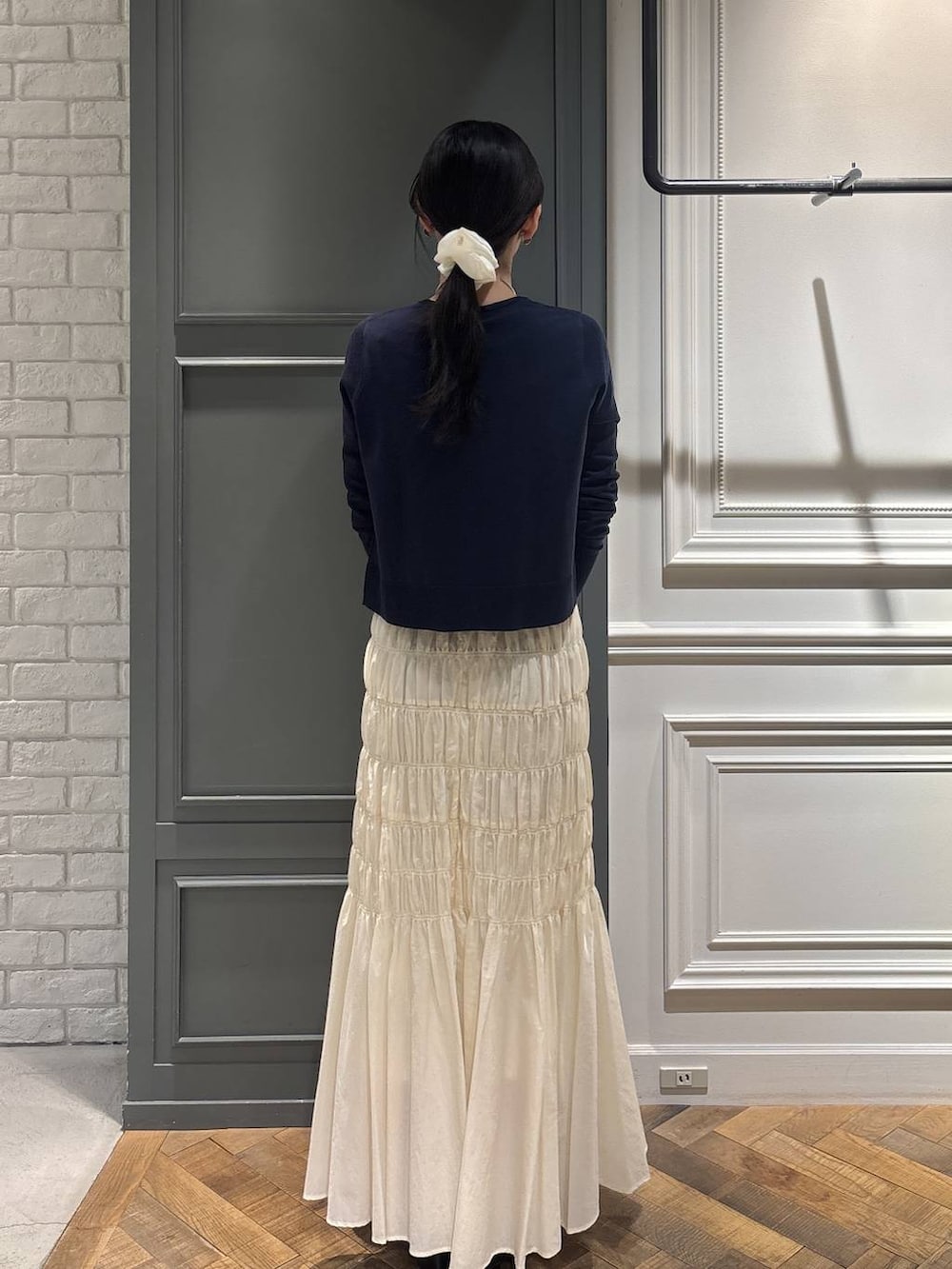 ブラック系のショルダーバッグ、ホワイト系のスカート、ブルー系のカーディガン/ボレロを着用したレディースの冬コーディネートの2枚目の写真