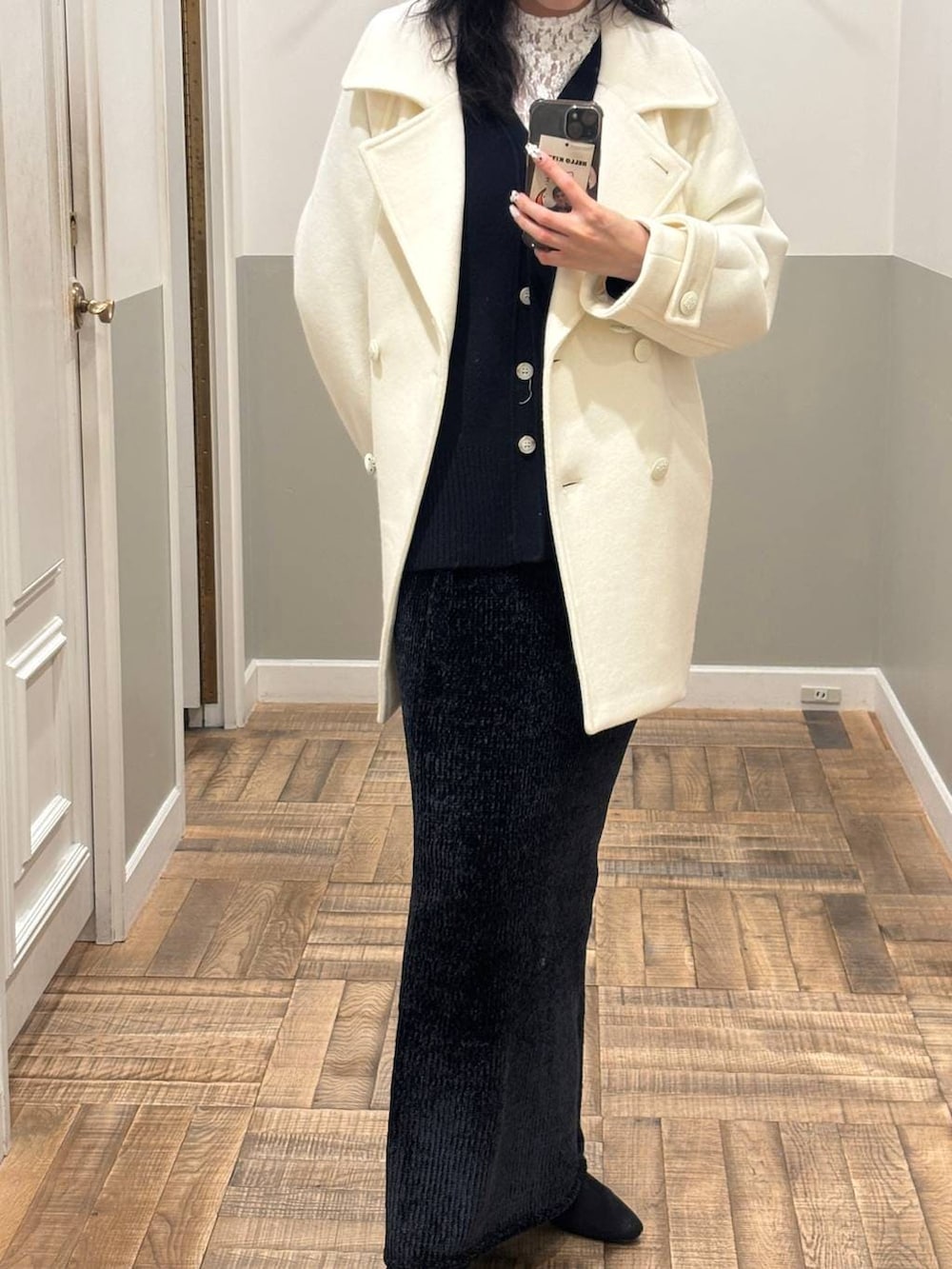 ホワイト系のピーコート、ブルー系のカーディガン/ボレロ、ブラック系のブーツを着用したレディースの冬コーディネートの2枚目の写真