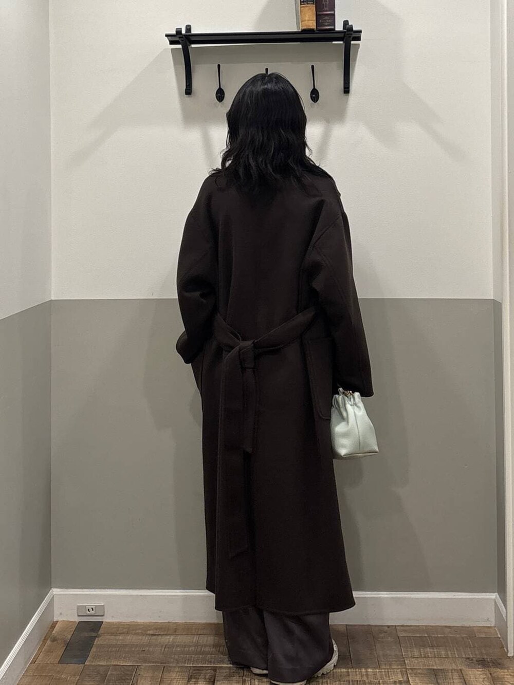 ブラウン系のステンカラーコート、グレー系のカーディガン/ボレロ、グリーン系のショルダーバッグを着用したレディースの秋コーディネートの3枚目の写真