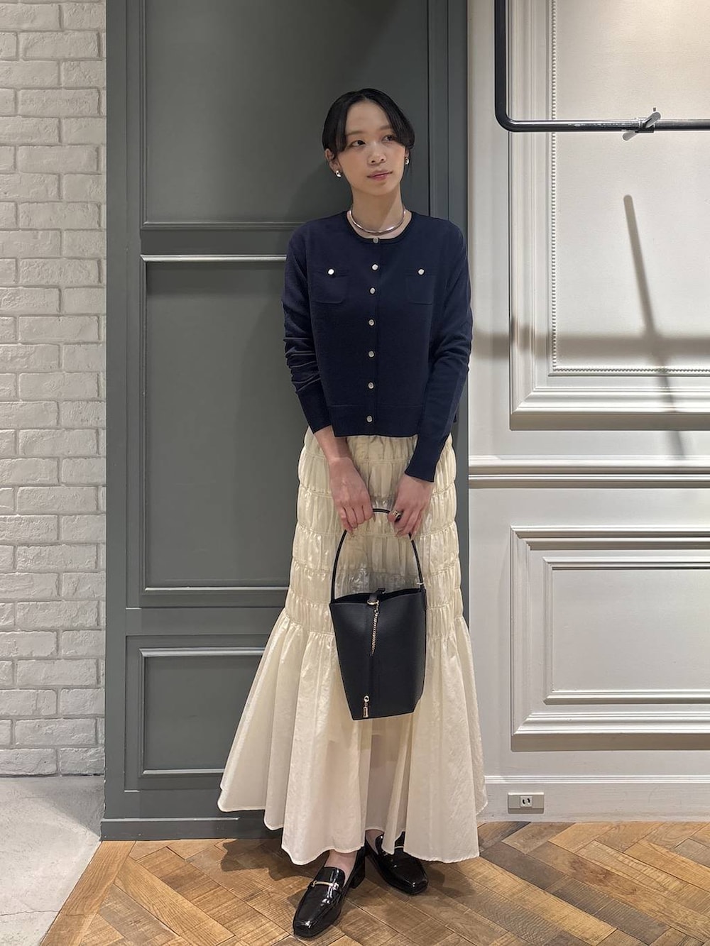 ブラック系のショルダーバッグ、ホワイト系のスカート、ブルー系のカーディガン/ボレロを着用したレディースの冬コーディネートの3枚目の写真
