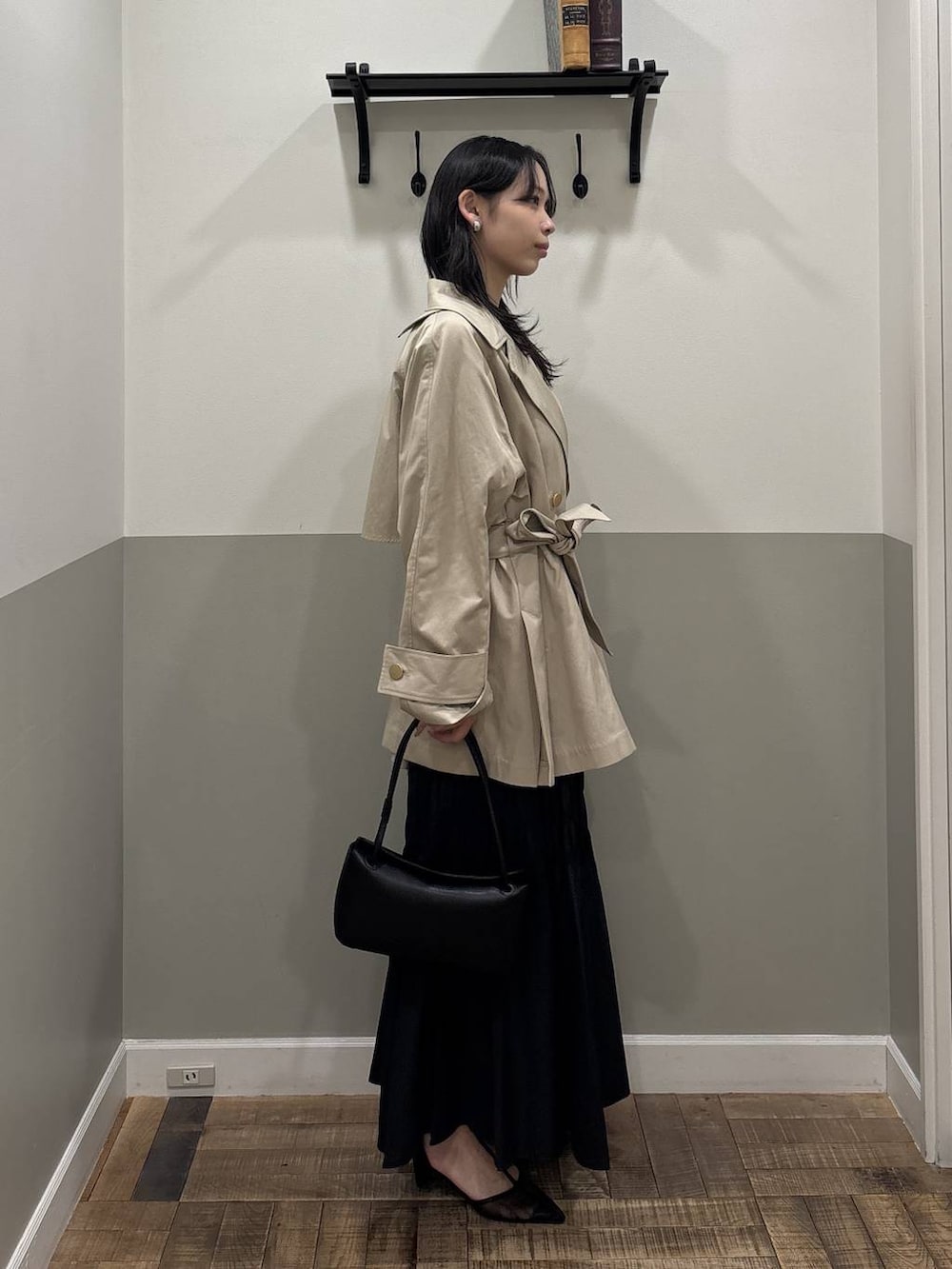 ベージュ系のトレンチコート、ブラック系のショルダーバッグ、ブラック系のスカートを着用したレディースの冬コーディネートの2枚目の写真