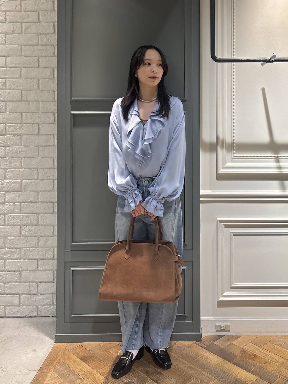 ブラウン系のショルダーバッグ、ブルー系のデニムパンツ、ブラック系のローファーを着用したレディースの冬コーディネートの3枚目の写真