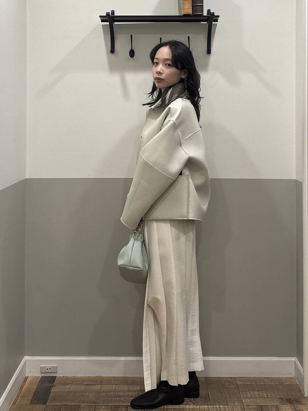 グリーン系のショルダーバッグ、ベージュ系のブルゾン、ホワイト系のスカートを着用したレディースの冬コーディネートの3枚目の写真