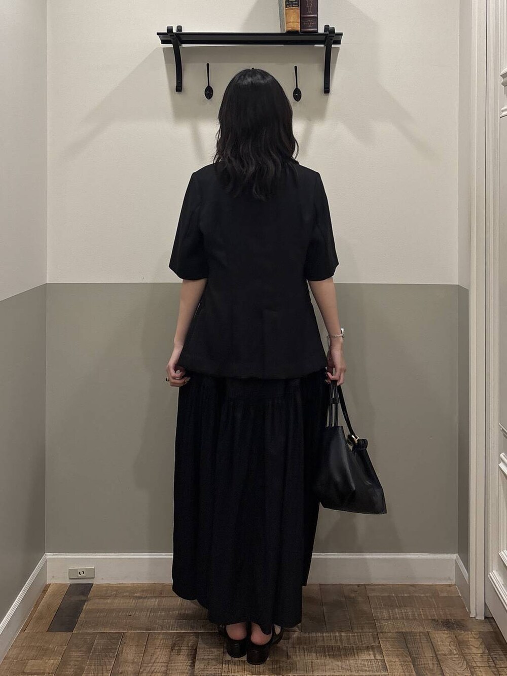 ブラック系のショルダーバッグ、ブラック系のパンプス、ブラック系のノーカラージャケットを着用したレディースの春コーディネートの2枚目の写真