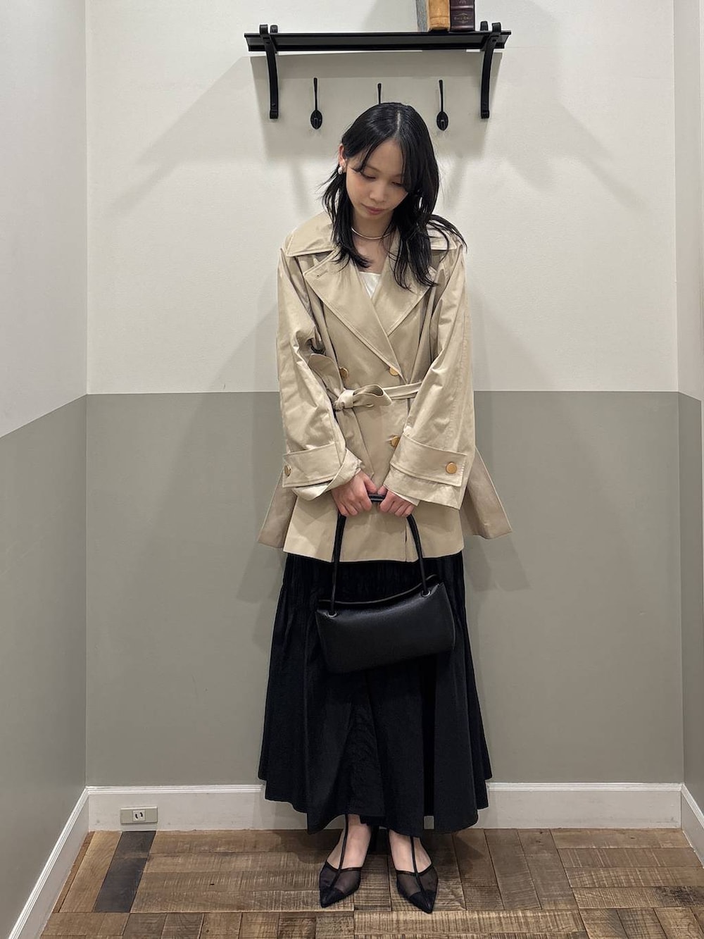 ベージュ系のトレンチコート、ブラック系のショルダーバッグ、ブラック系のスカートを着用したレディースの冬コーディネートの3枚目の写真