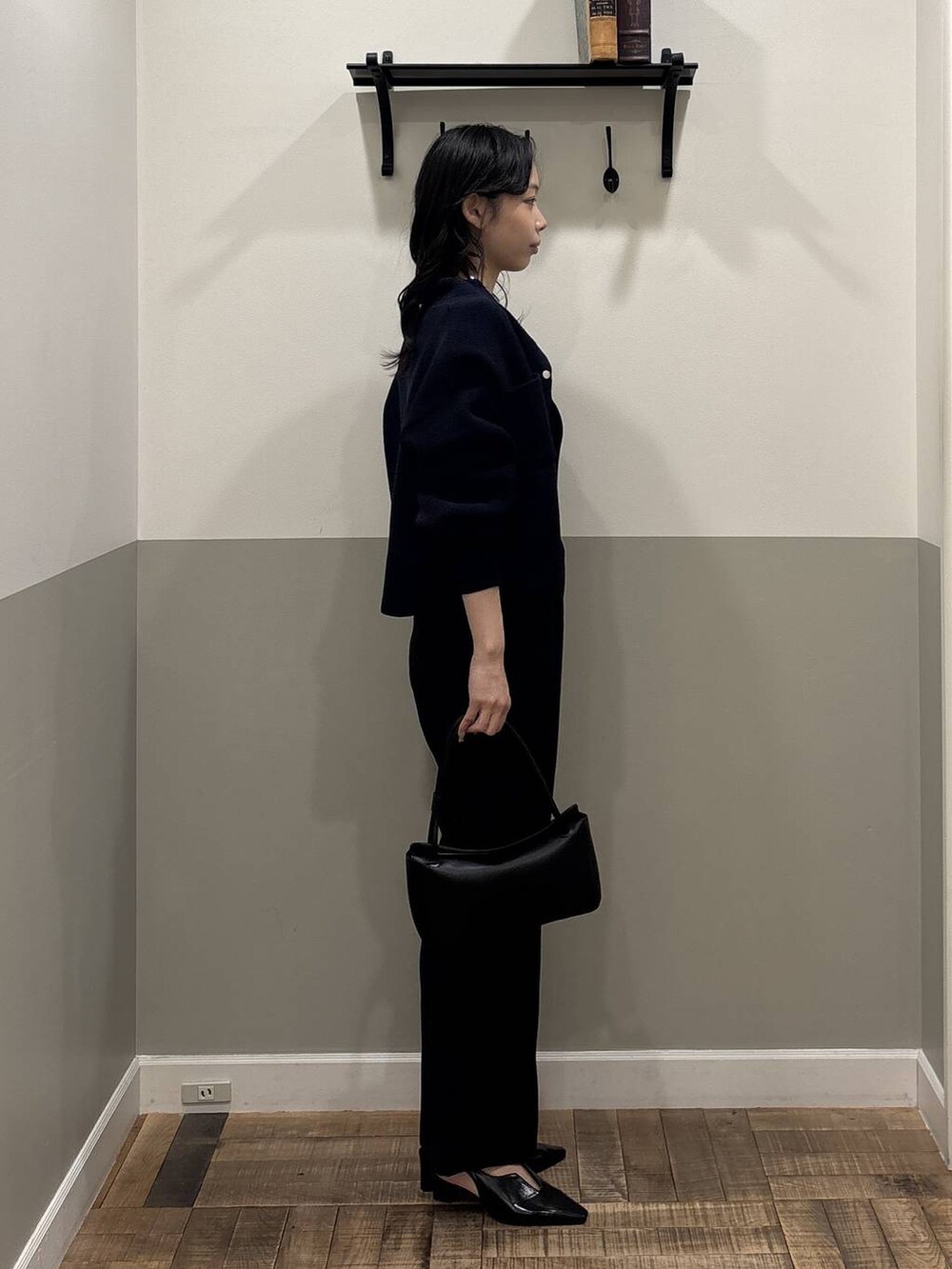 ブラック系のスラックス、ブラック系のパンプス、ブラック系のショルダーバッグを着用したレディースの冬コーディネートの2枚目の写真