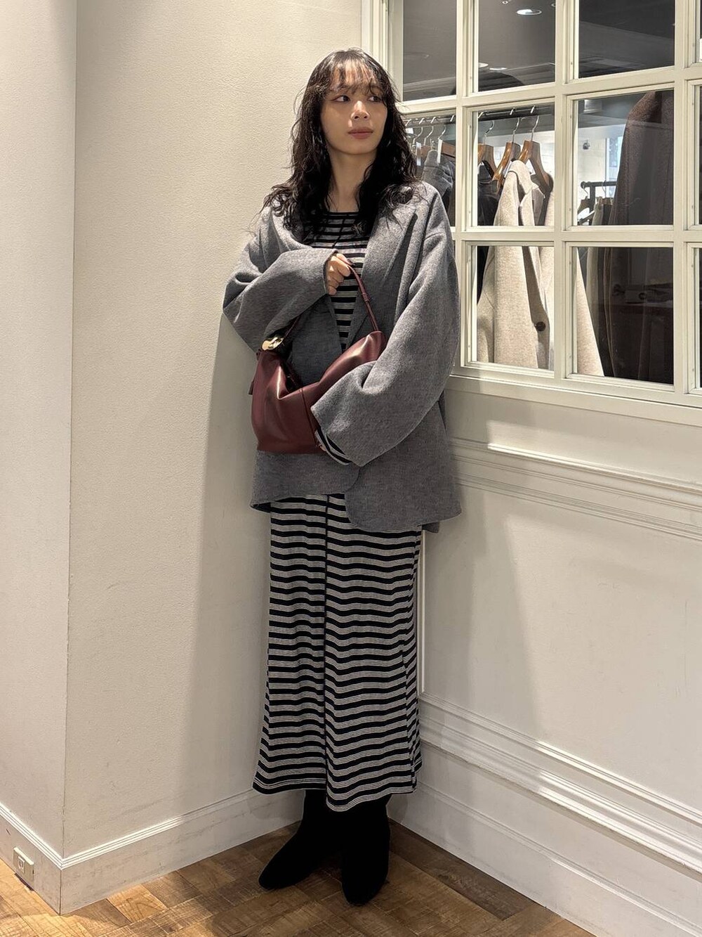 グレー系のテーラードジャケット、ブラック系のワンピース、ブラック系のブーツを着用したレディースの秋コーディネートの2枚目の写真