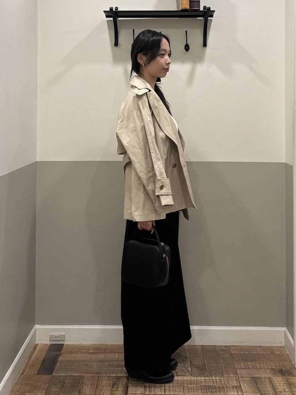 ベージュ系のトレンチコート、ホワイト系のカーディガン/ボレロ、ブラック系のショルダーバッグを着用したレディースの春コーディネートの2枚目の写真