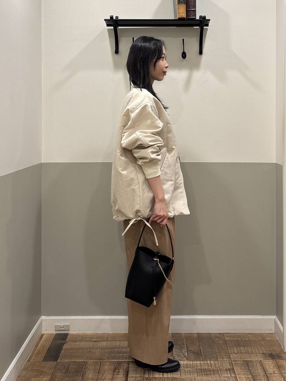 ベージュ系のMA-1、ブラック系のショルダーバッグ、ホワイト系のカーディガン/ボレロを着用したレディースの春コーディネートの2枚目の写真